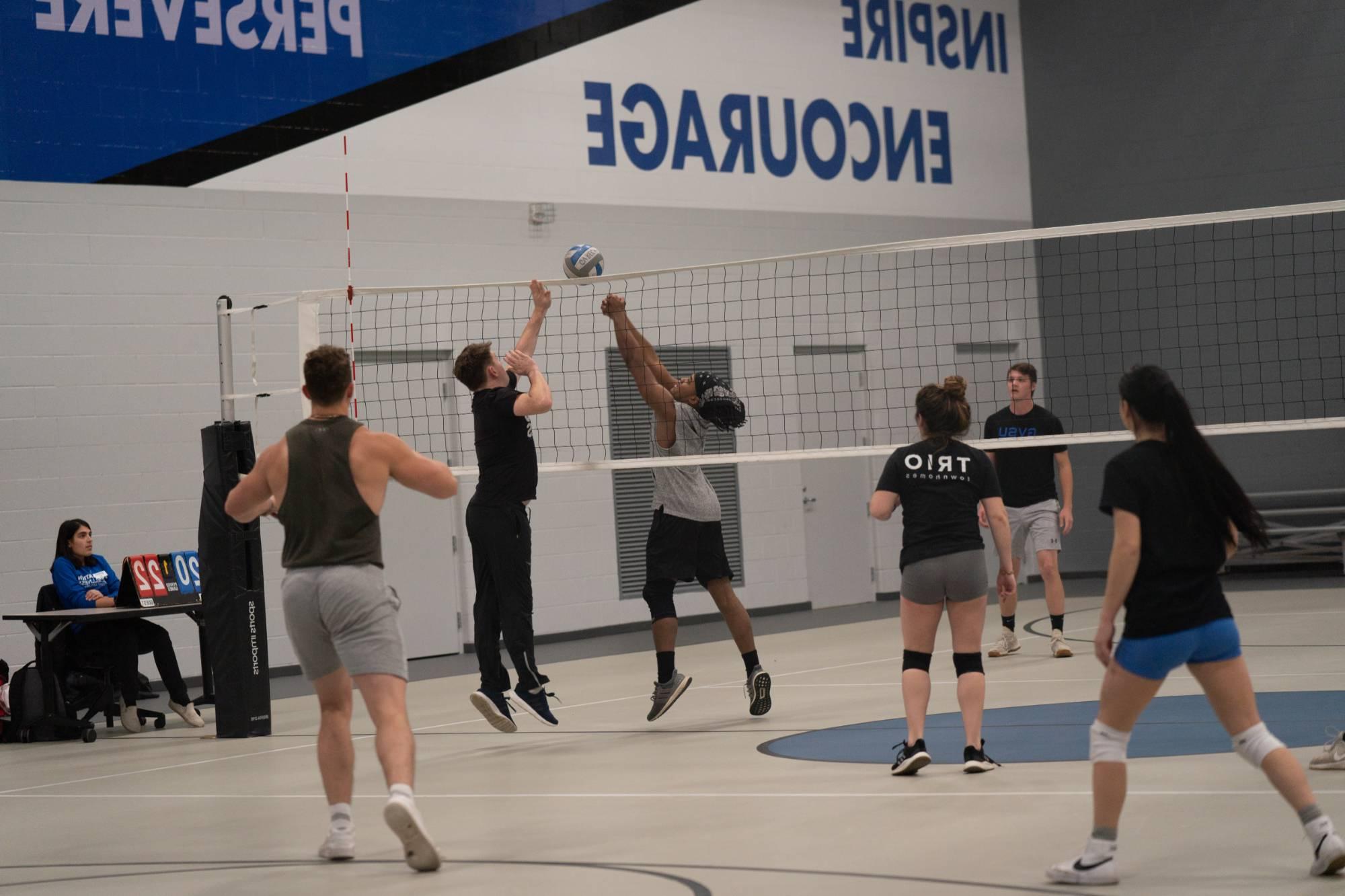 volleyball players playing the ball at the net